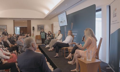 A panel of women speaking to a crowd on a stage