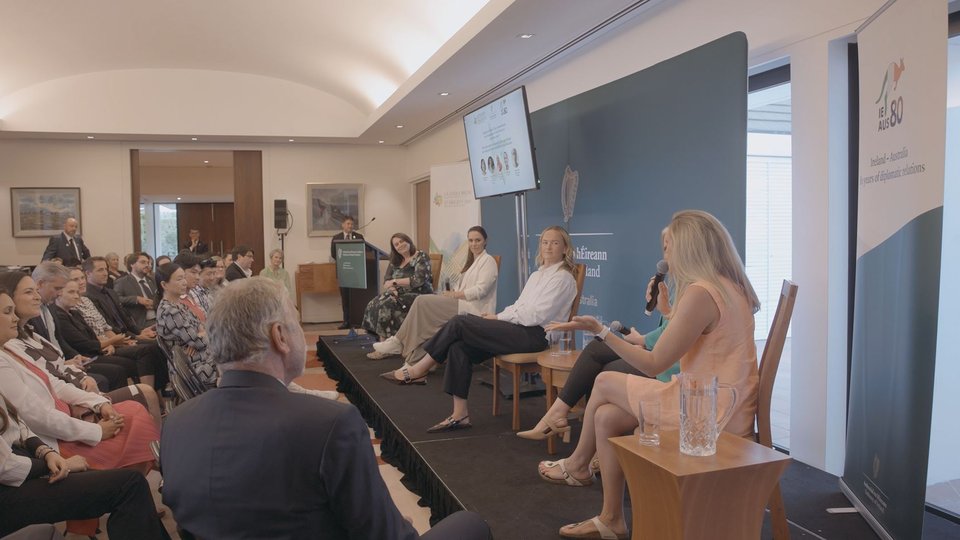 A panel of women speaking to a crowd on a stage