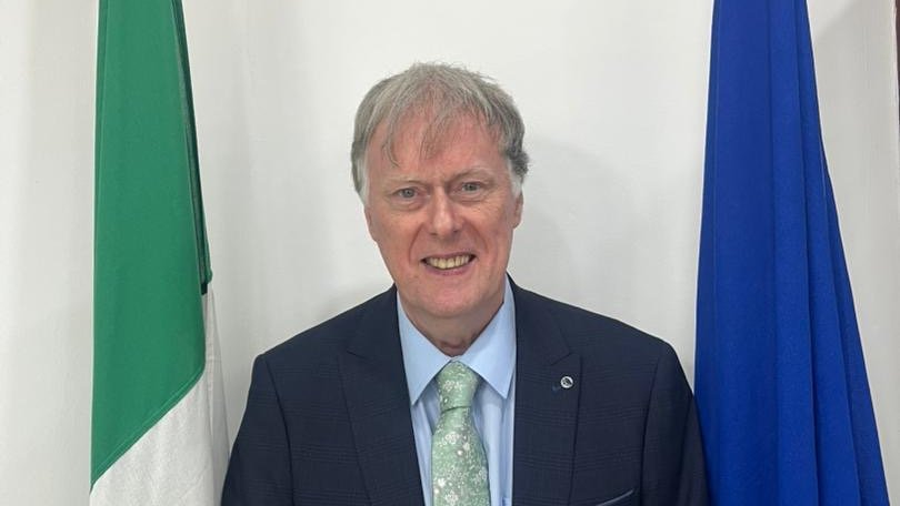 Ambassador Patrick McManus in front of the Irish and European Flags