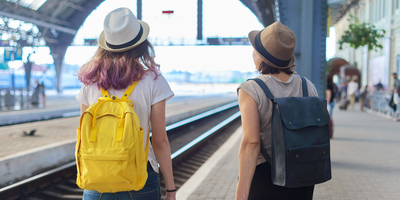 Two students wearing backpacks in a train station