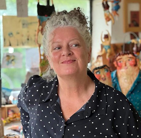 Photo of a smiling woman with grey hair, wearing a navy spotty blouse.