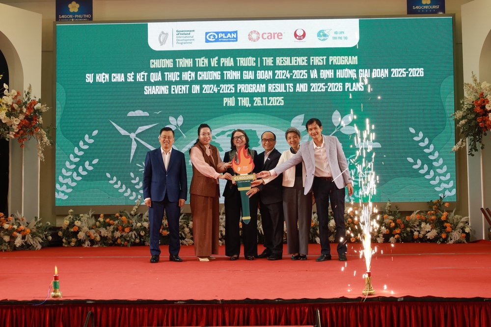 A group of people, including Ambassador Deirdre Ní Fhallúin, stand on a stage during the announcement of funding for a development cooperation programme in Vietnam.