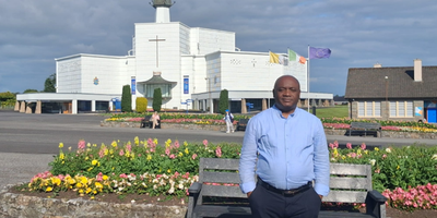 Man in blue shirt standing in front of a white church
