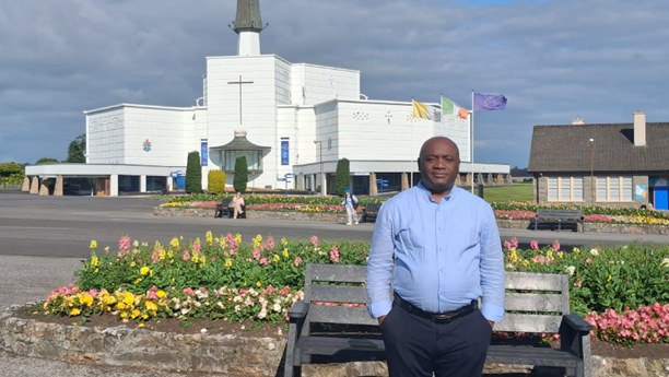 Man in blue shirt standing in front of a white church