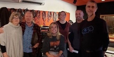 six people standing in a recording studio with poor light
