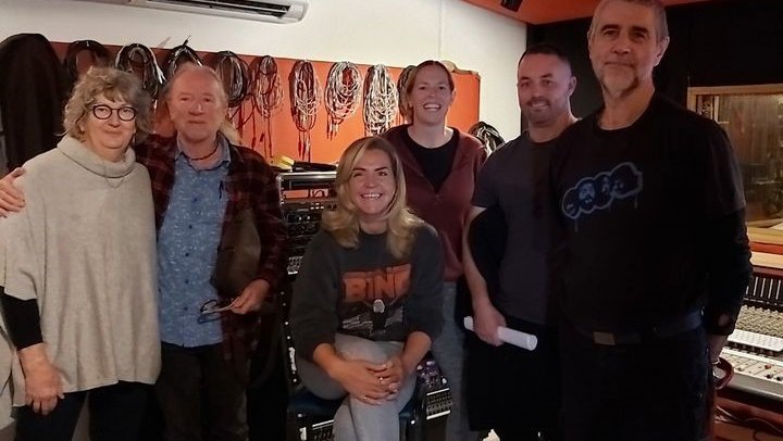 six people in a recording studio with cables hanging behind them