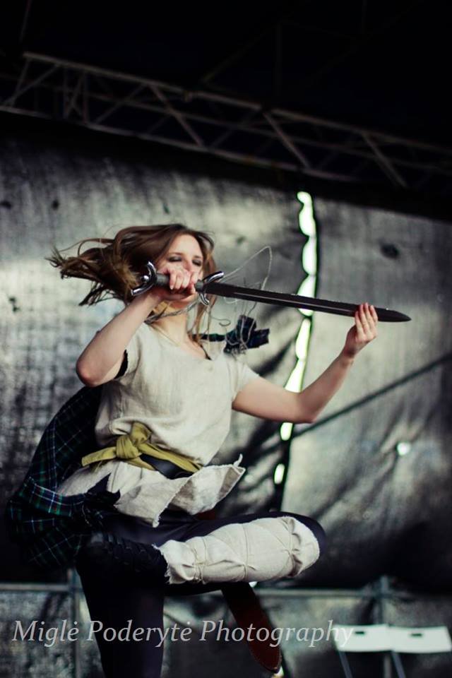 A dancer in costume dancing on a stage with a sword