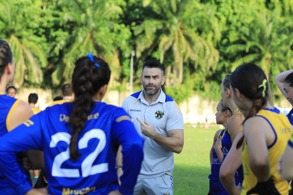 Couch speaking to ladies Gaelic football team in Orang Éire kits