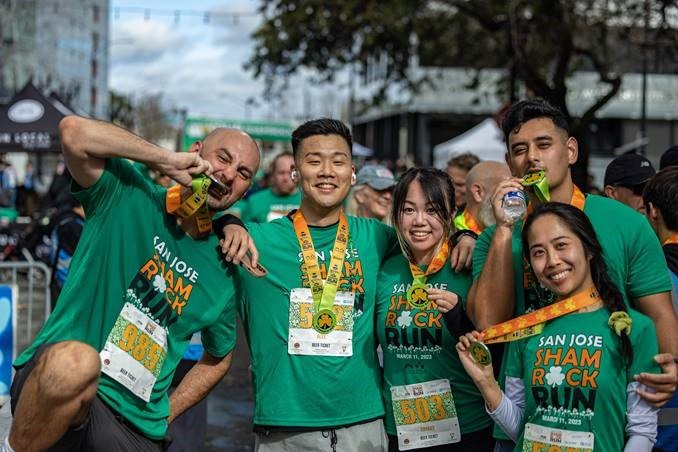 people posing wearing green tshirts and medals for the Shamrock Run in San Francisco