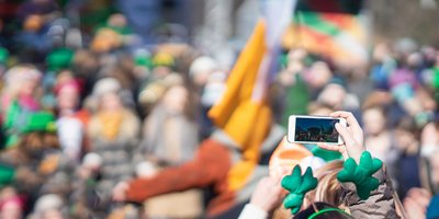 somebody wearing shamrock headband taking a photo at St Patricks Day parade