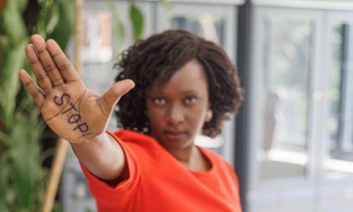 woman holding up her palm to camera with STOP written on it