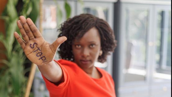 Woman holding her palm to the camera with STOP written on it