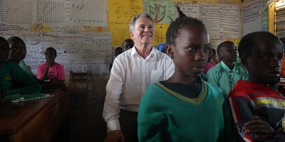 Minister Seán Fleming sitting in a classroom amongst children.