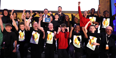 Our World Awards School of the Year winners 2026 on a stage cheering with Minister Richmond