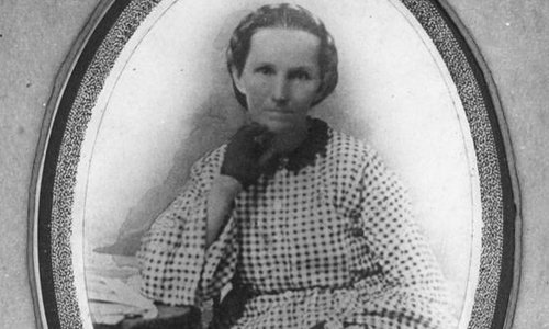A very old black and white photo of a woman in an old fashioned blouse