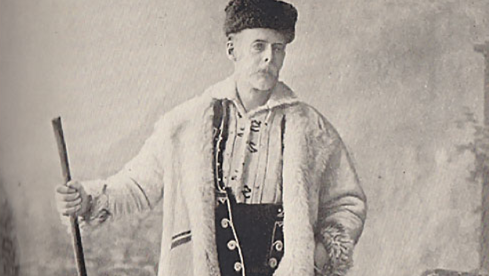 Old sepia photograph of a man in traditional Bulgarian dress standing with a shovel in his hand
