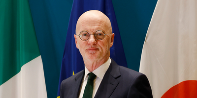 Man in a suit in front of Irish and Japanese national flags