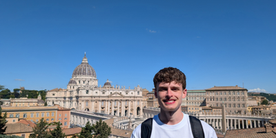 Young man in grey jumper in front of the Vatican