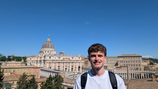 Man in grey jumper in front of the Vatican