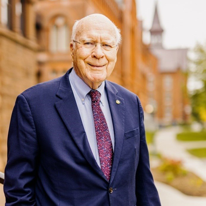 Man standing in a suit outside a redbrick building