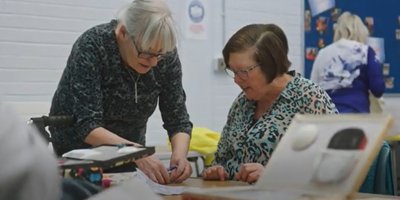Two women leaning over a desk