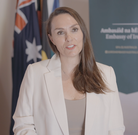 A woman standing in front of Irish, European and Australian flags