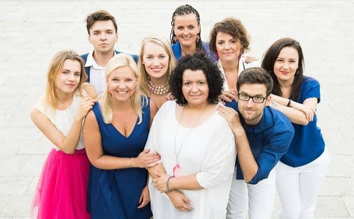 A group of people in white, navy blue and pink clothes smile for the camera