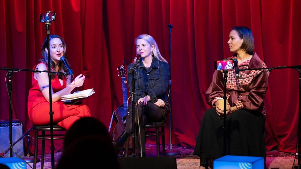 Three woman talking into mics on a stage