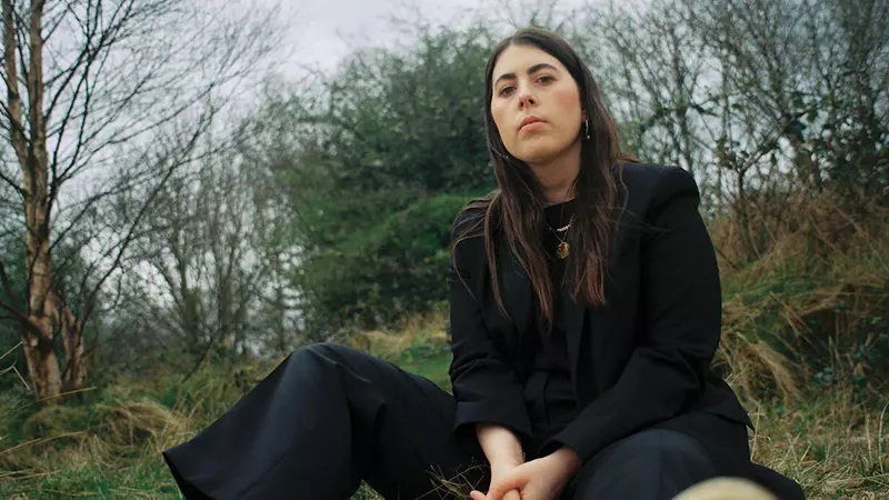 a young woman dressed in black sitting in the woods