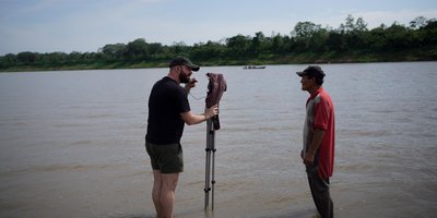 Journalist recording and interviewing a man in a river
