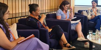 four women sitting on armchairs as part of a panel