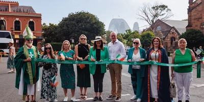 people in a line holding a green sash with the harbour bridge in the background