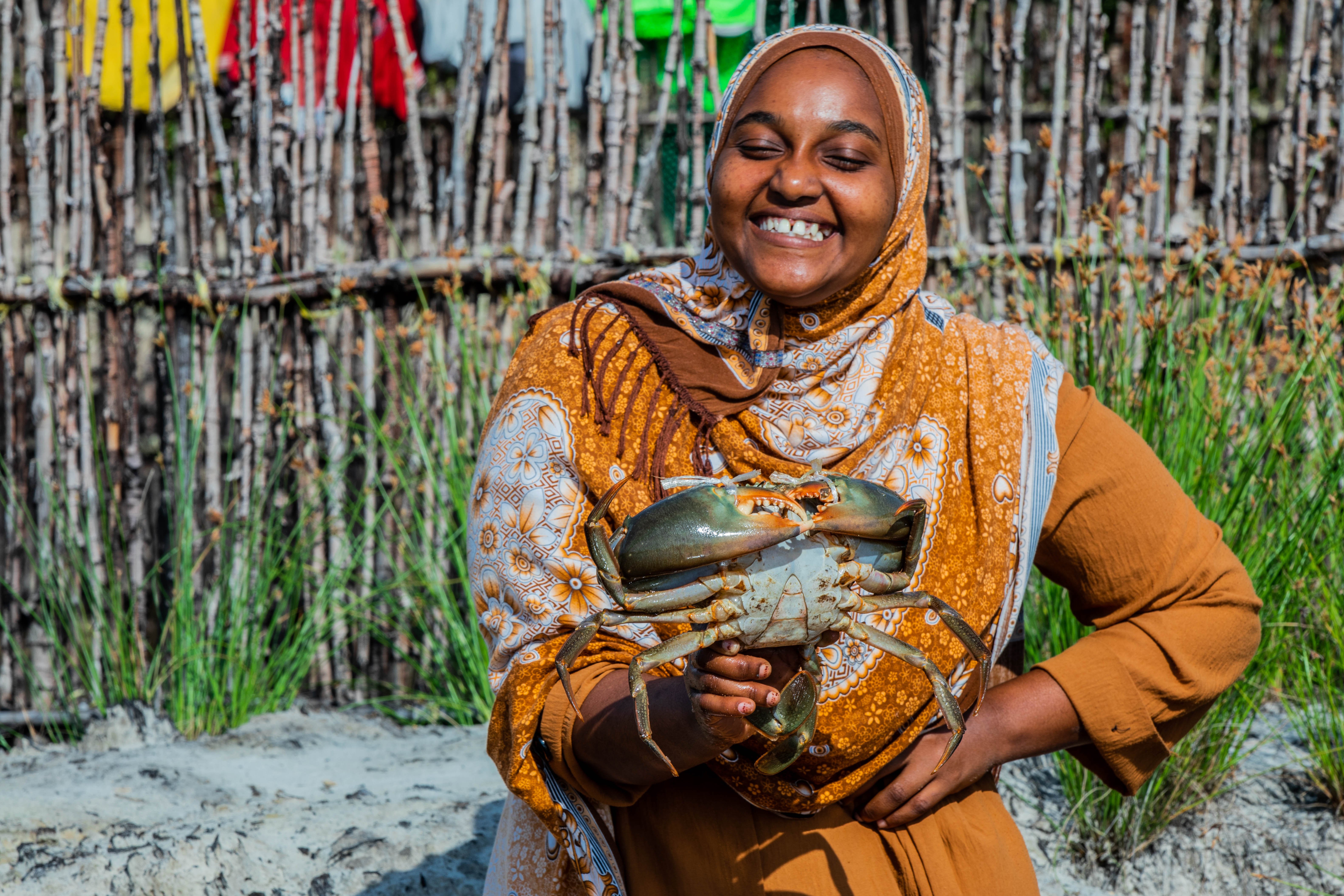 A woman in Tanzania participating in a food programme, holding up a crab