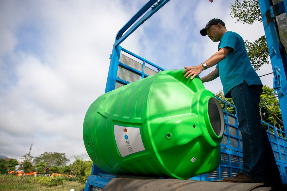 A Vietnamese man handles a large water container provided by UNICEF, showing the Irish Aid logo