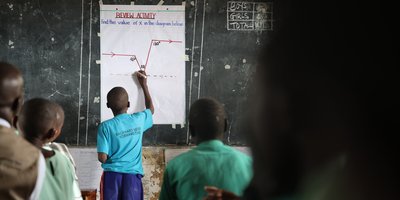 Student writing on board in classroom in Uganda