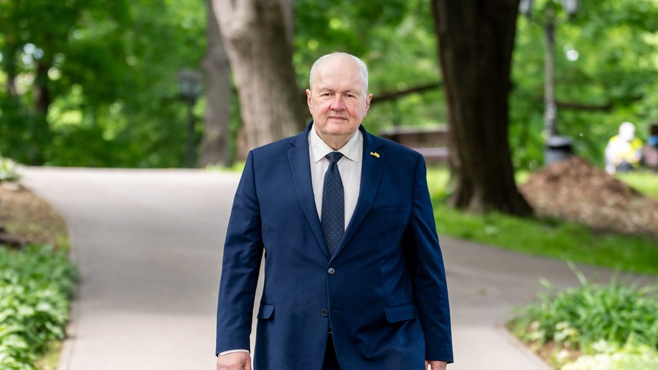 Uģis Rotbergs, walking through a park in a suit
