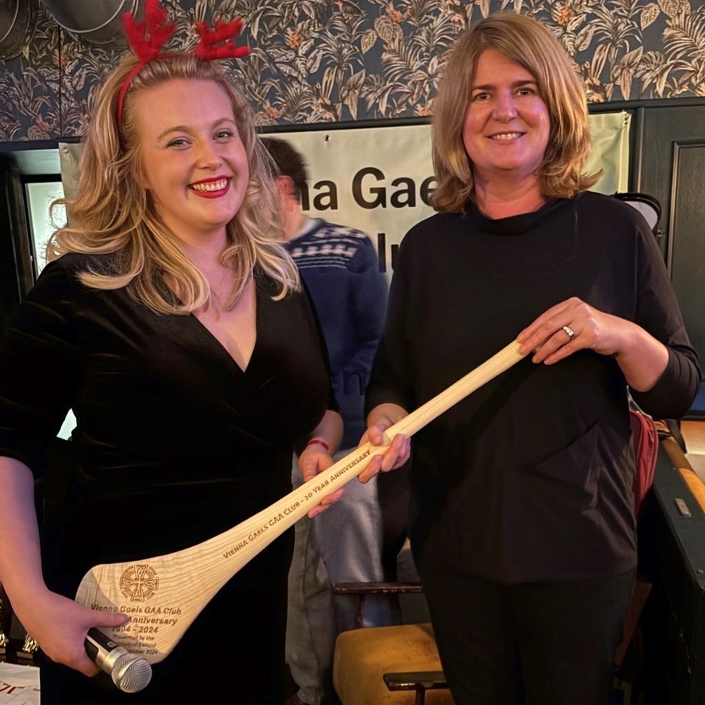 Ambassador of Ireland to Austria, Barbara Cullinane, presenting Vienna Gaels GAA  Chairperson, Axelina Heagney, with a commemorative hurl for the Vienna Gaels 20th Anniversary event in November 2024