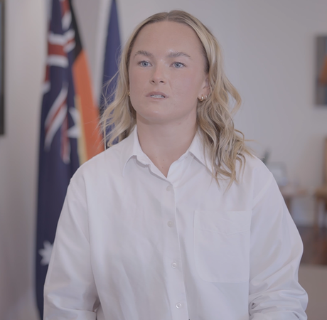A woman standing in front of Irish, European and Australian flags