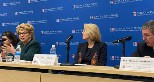 two women and a man sitting at a podium with microphones, the woman on the left is speaking
