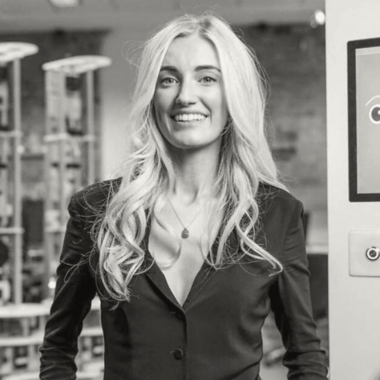 Woman in a suit with her hands in her pocket, smiling