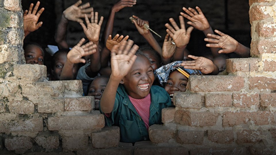 Children waving out a window.