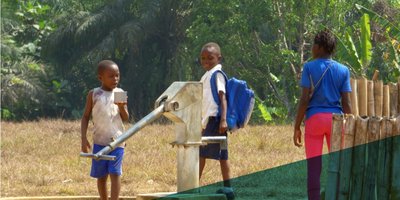 Three young boys getting water from a water pump.