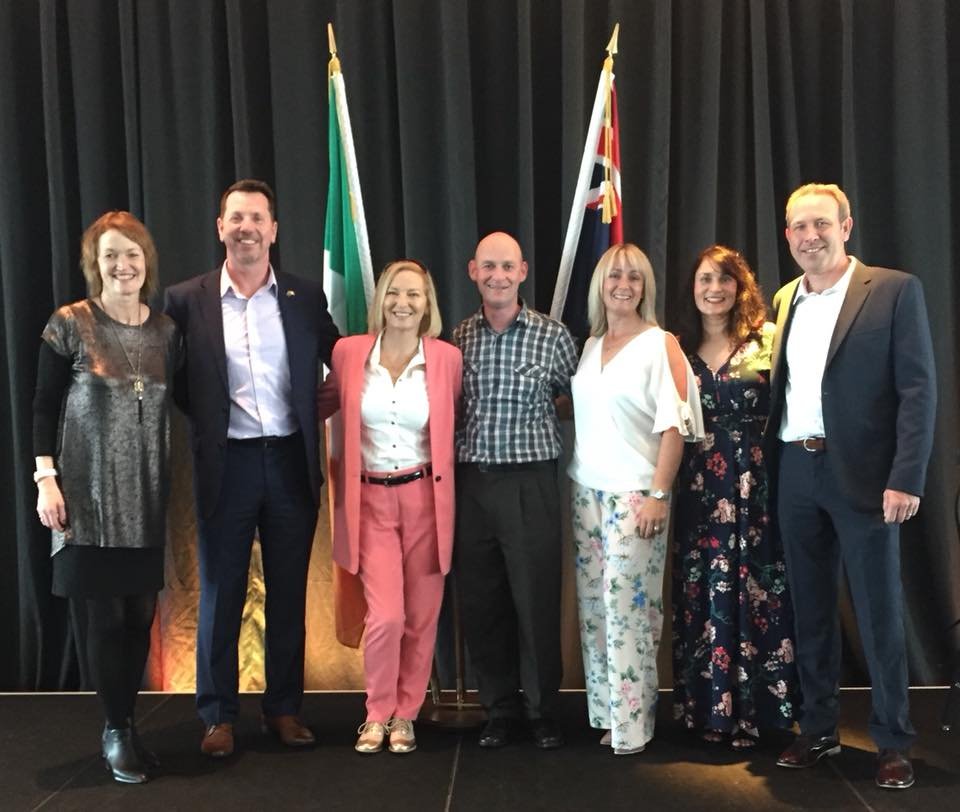 A group photo in front of the Irish and New Zealand flags.