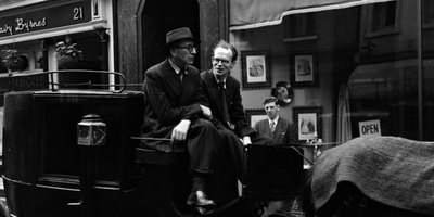 Patrick Kavanagh and Anthony Cronin seated on carriage outside Davy Byrnes pub, Bloomsday, Duke Street, Dublin