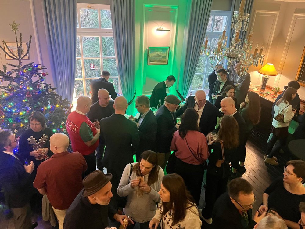 People gathered in groups chatting; Christmas tree in the corner