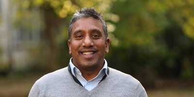 Man smiling at the camera with foliage in the background