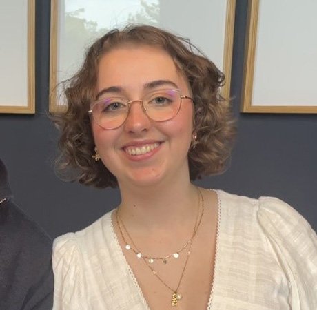 a young woman with fair curly hair wearing a white top