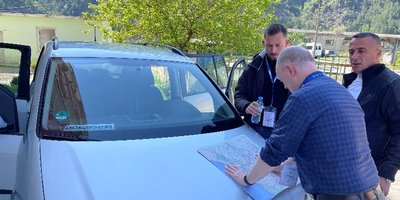 Ralph poring over a map with driver and interpreter to decide their route.