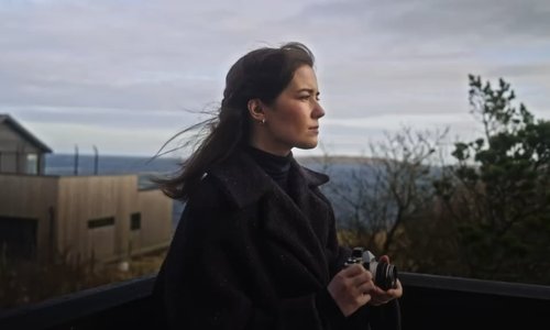 Woman holding a camera gazing off into the distance