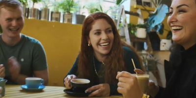 three people laughing over coffee